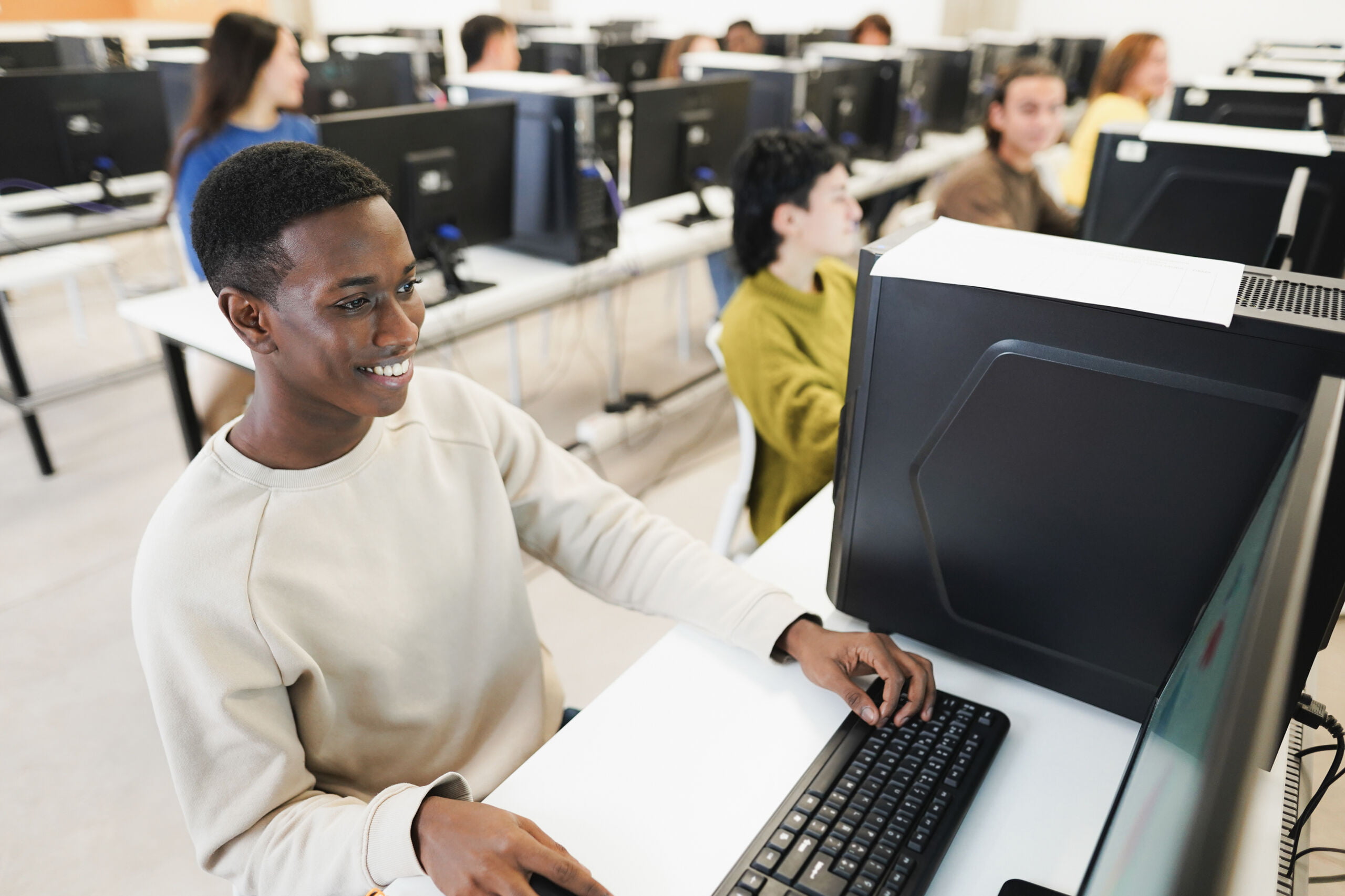 Young african student using computer inside computer room at school – Focus on left eye PRIVATE